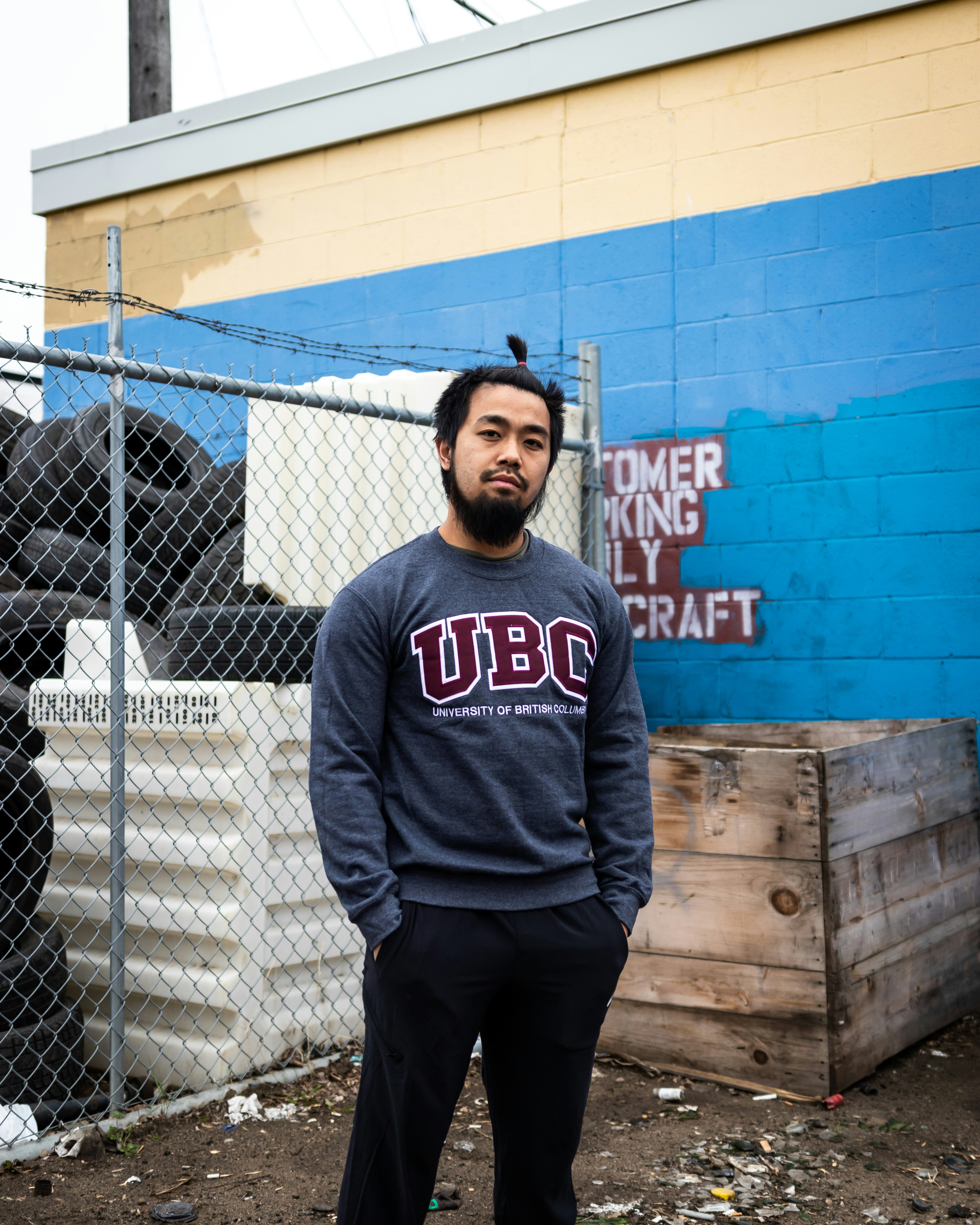 man in blue and white pullover hoodie standing beside chain link fence